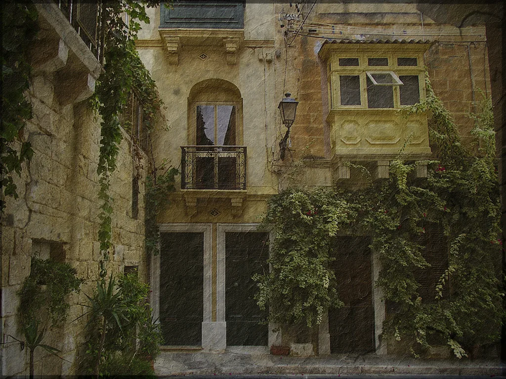 A weathered stone house with a balcony in Birgu.
