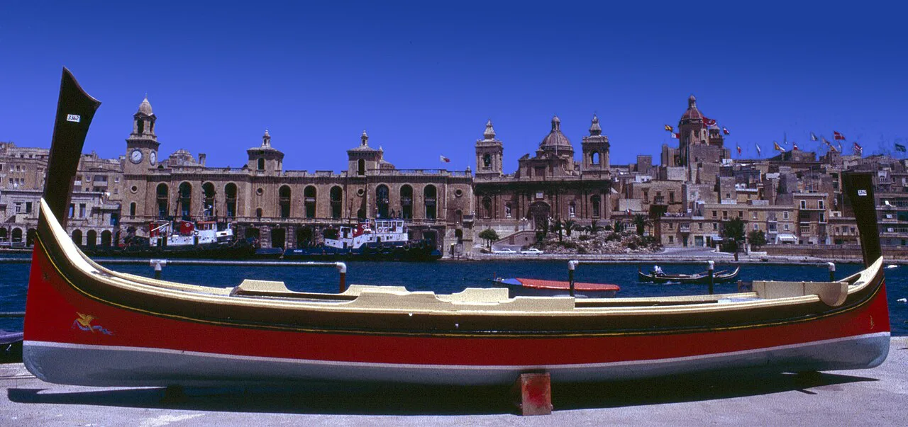 A luzzu boat with Birgu's waterfront behind, near Cospicua.