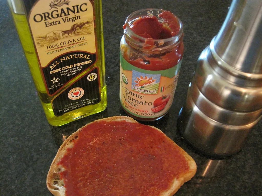 Bread spread with tomato paste beside olive oil, the base of ħobż biż-żejt.