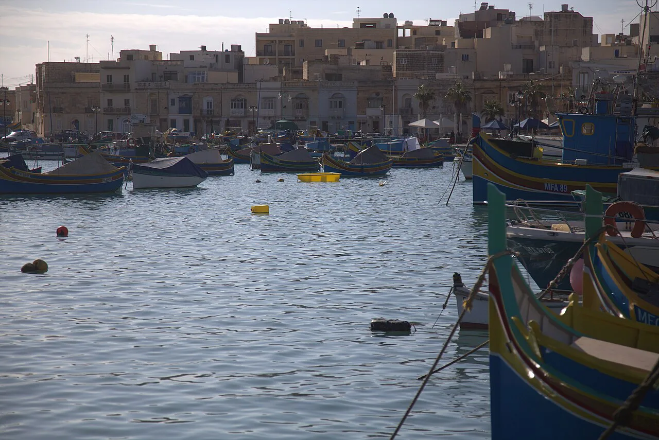 Brightly painted luzzu boats and waterfront houses in Marsaxlokk.