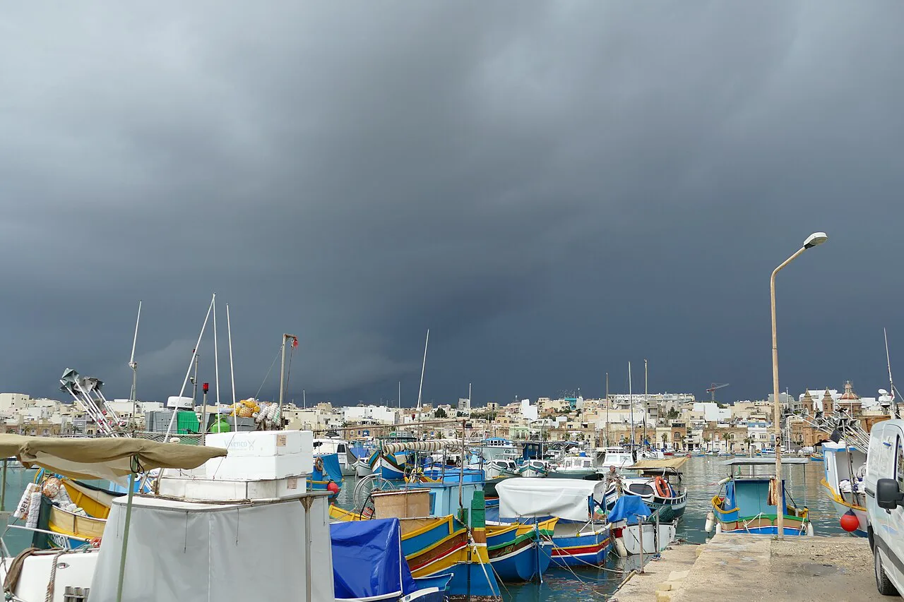 Luzzu boats in Marsaxlokk harbour under stormy skies.