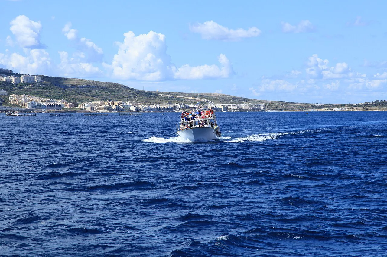 A boat crossing Mellieħa Bay with the village behind.
