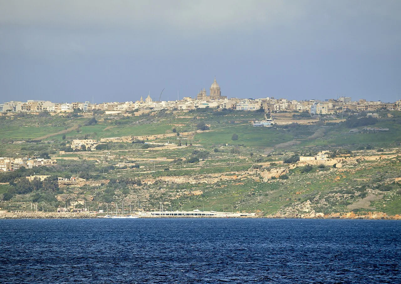 Gozo's green coast and hilltop town seen from the sea.