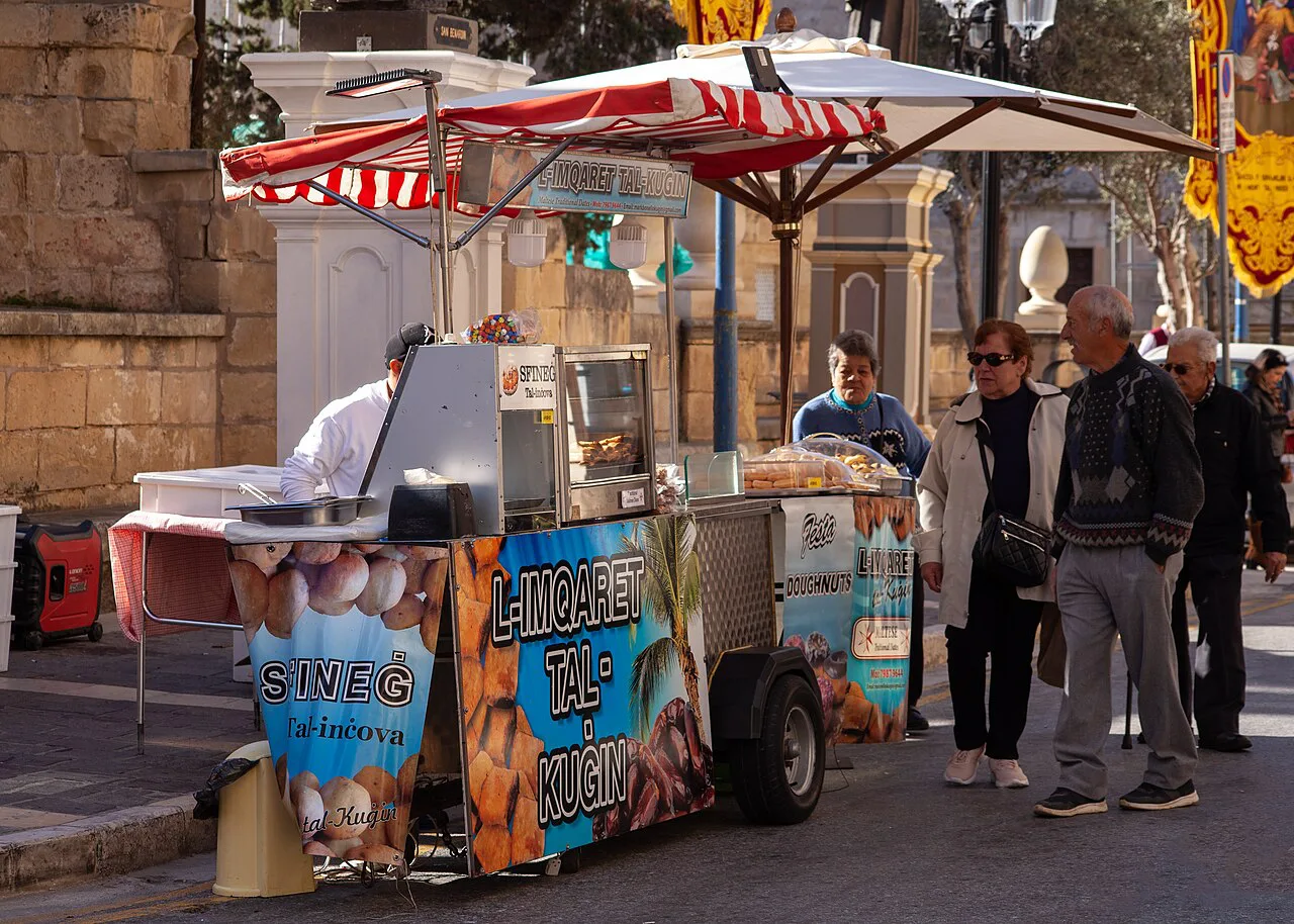 Sfineġ fritters and date-filled mqaret at a Maltese street stall.