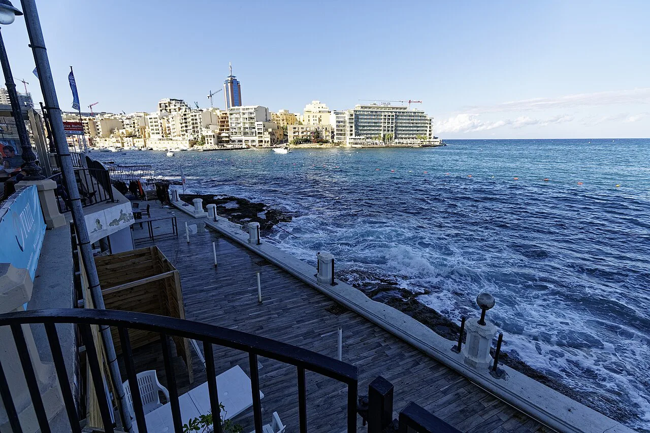 The coast at St George's Bay in St Julian's, with the towers of Sliema beyond.