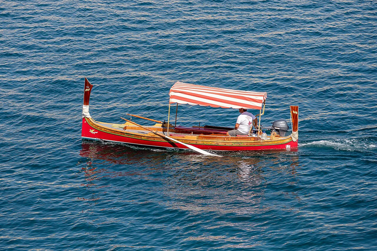 A traditional dgħajsa water taxi crossing the harbour.